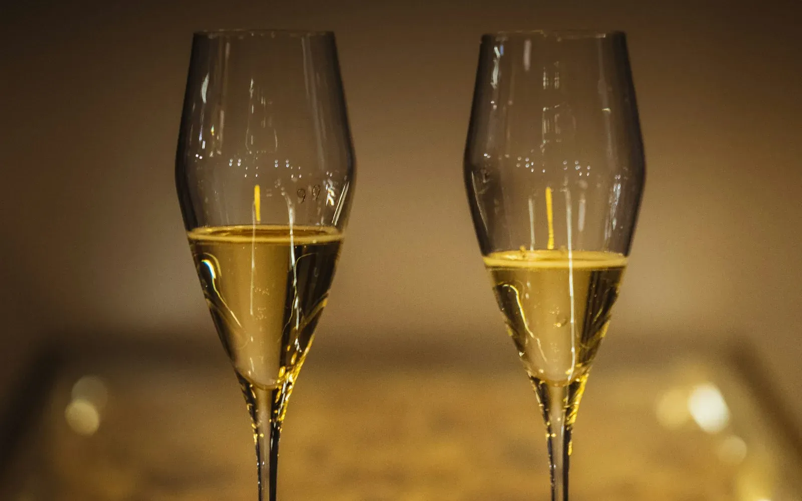 Zwei Gläser Champagner vor warmem, unscharfem Hintergrund