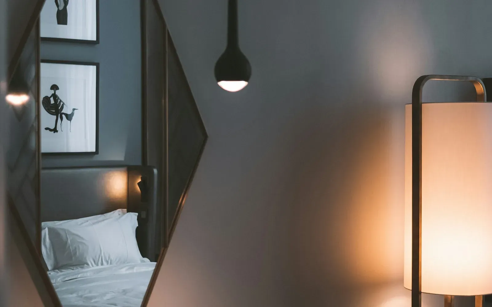 Gedämpft beleuchtetes Hotelzimmer mit Stehlampe und Bett im Spiegel