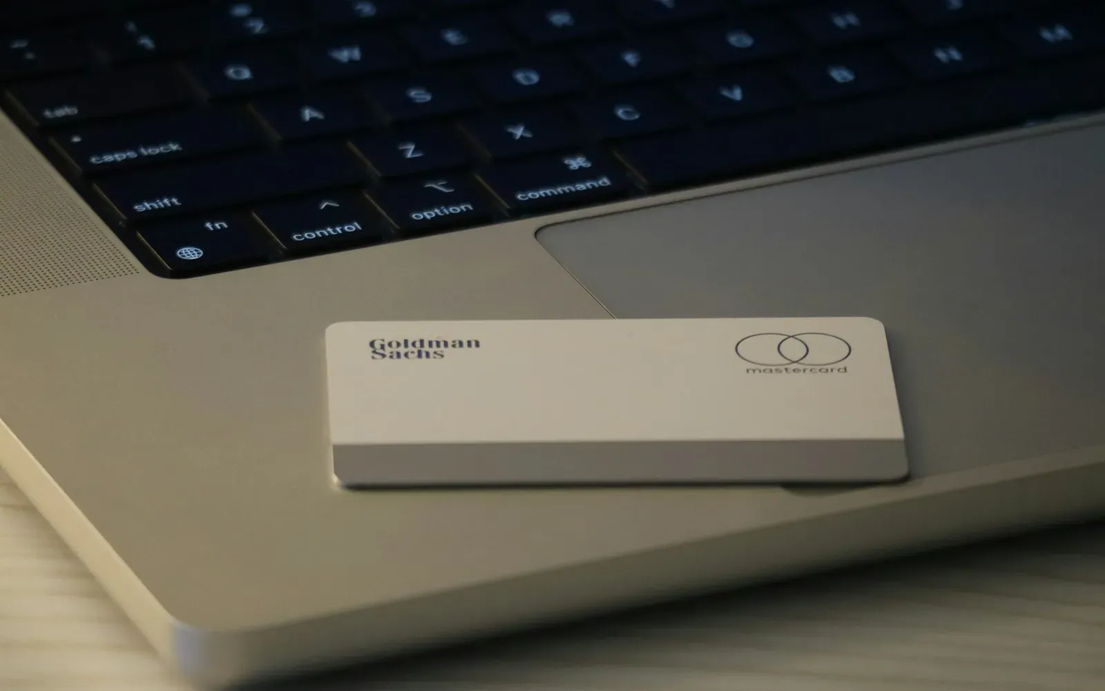 Silberne Kreditkarte liegt auf der Handballenauflage eines aufgeklappten Laptops