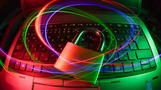 Vorhängeschloss auf einer Laptop-Tastatur mit Lichtspuren – Pornos sicher schauen