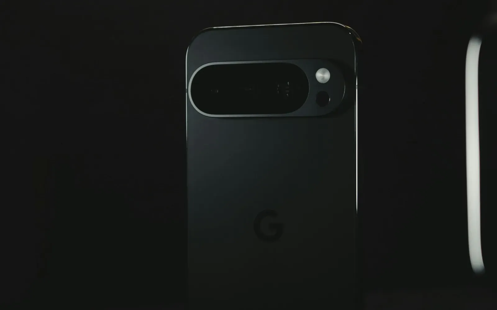 Dunkles Smartphone von hinten mit Kameraleiste vor schwarzem Hintergrund, seitlich ein heller Lichtstreifen – OnlyFans-Alternativen im Vergleich